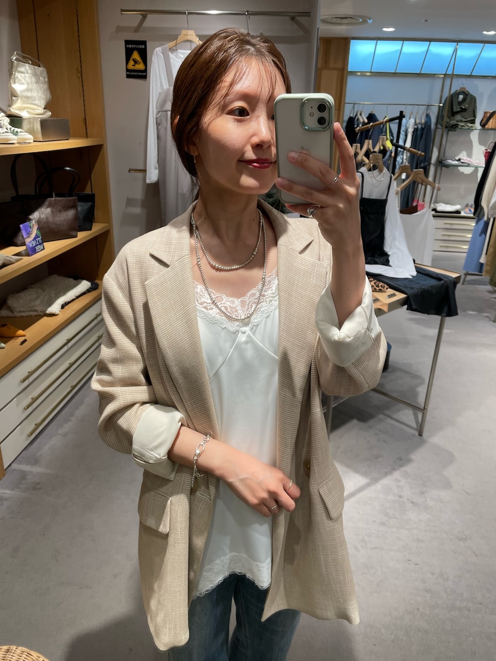 ベージュ系のテーラードジャケット、ブルー系のデニムパンツ、ホワイト系のキャミソールを着用したレディースの秋コーディネートの2枚目の写真