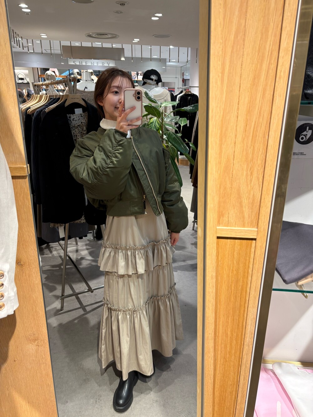 ベージュ系のワンピース、ホワイト系のニット/セーター、ブラック系のブーツを着用したレディースの冬コーディネートの2枚目の写真