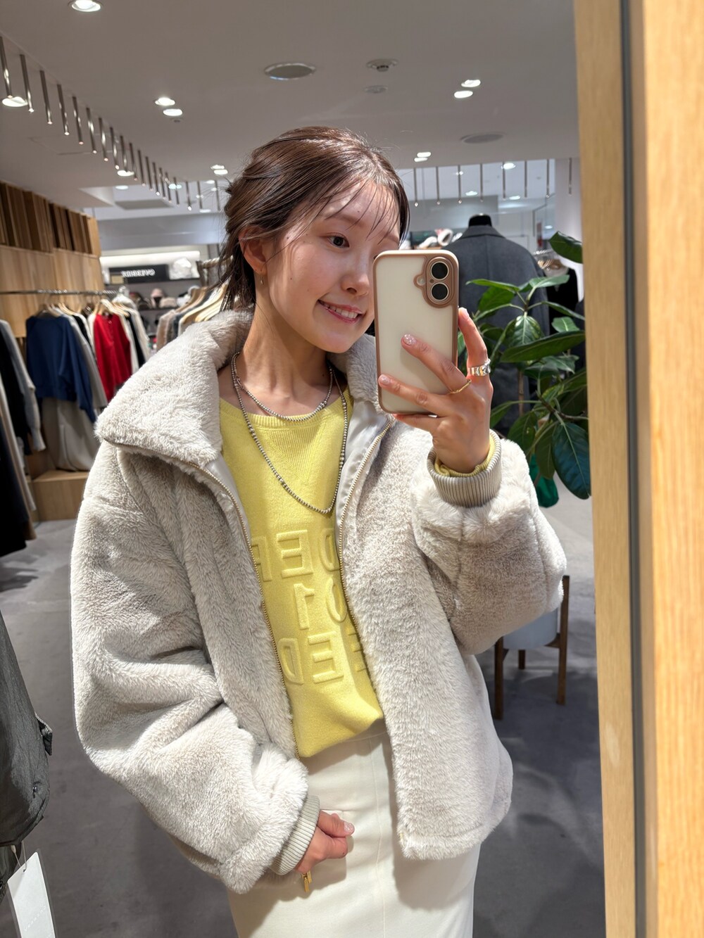 イエロー系のニット/セーター、ホワイト系のその他アウター、ホワイト系のスカートを着用したレディースの冬コーディネートの2枚目の写真