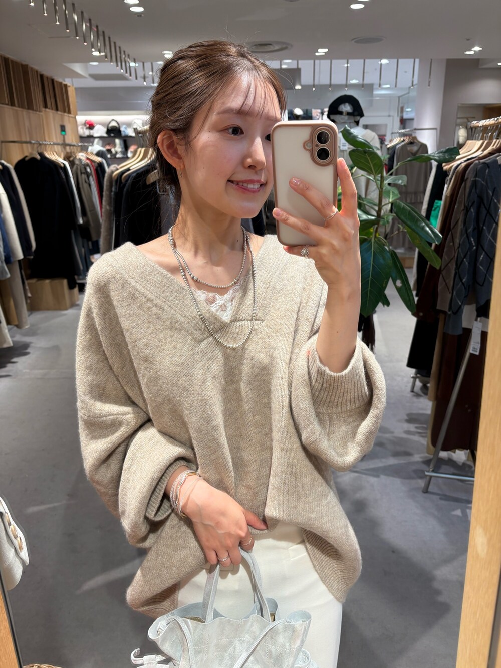 ベージュ系のニット/セーター、ホワイト系のスカート、レッド系のマフラーを着用したレディースの冬コーディネートの2枚目の写真