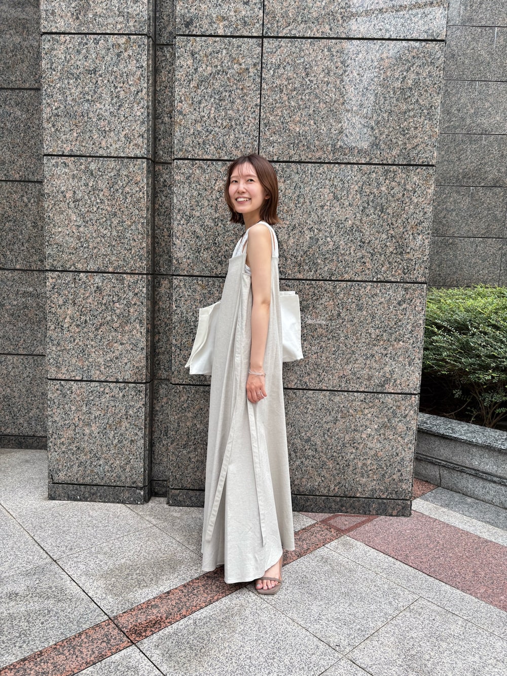 ベージュ系のワンピース、ホワイト系のTシャツ/カットソー、ホワイト系のトートバッグを着用したレディースの夏コーディネートの2枚目の写真