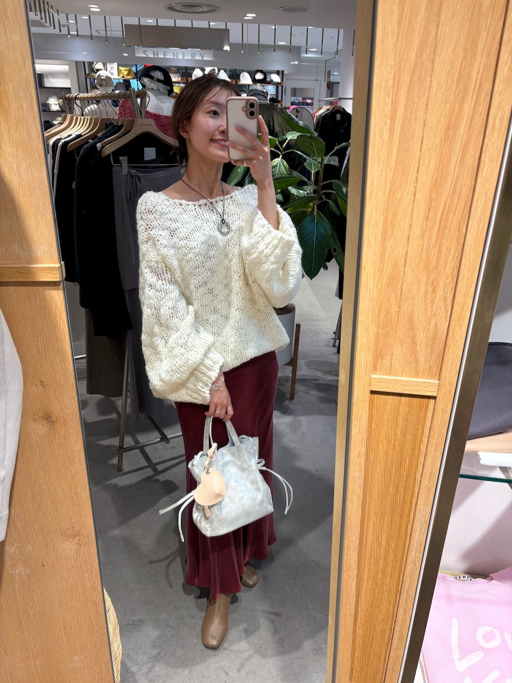 ホワイト系のニット/セーター、シルバー系のトートバッグ、レッド系のスカートを着用したレディースの冬コーディネートの2枚目の写真