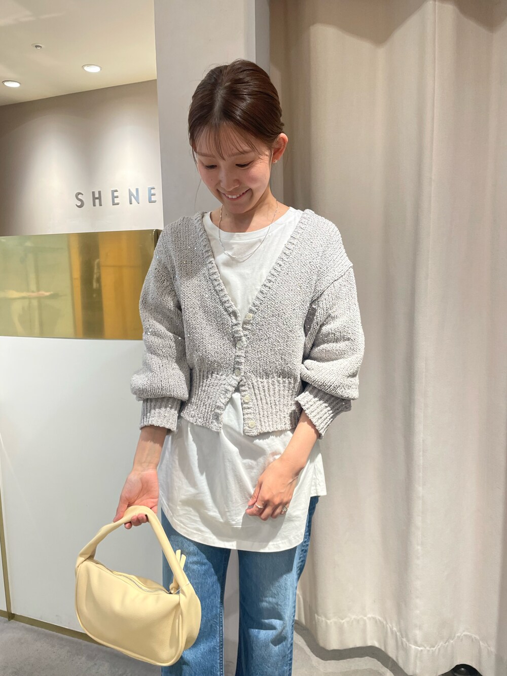 ブルー系のデニムパンツ、イエロー系のハンドバッグ、グレー系のカーディガン/ボレロを着用したレディースの冬コーディネートの2枚目の写真