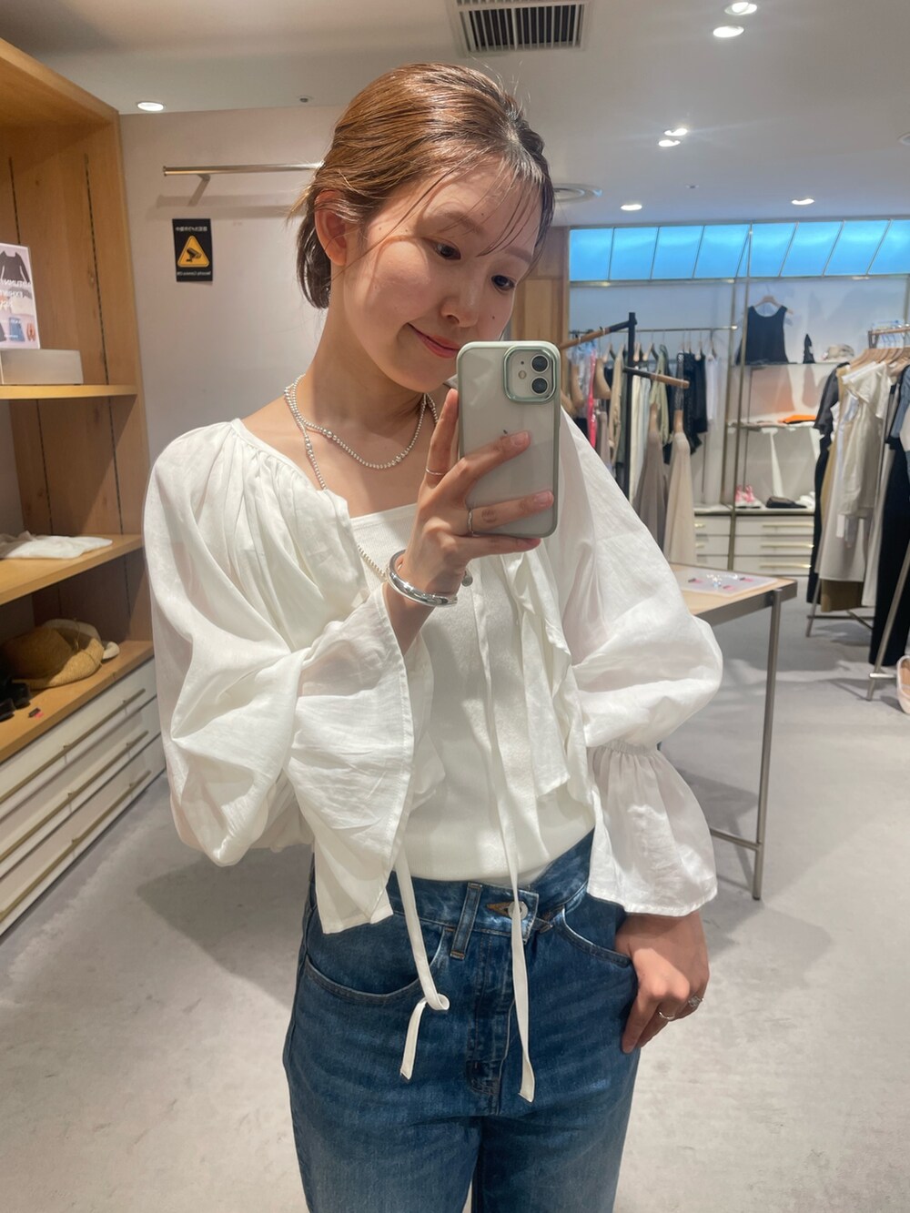 ホワイト系のシャツ/ブラウス、ブルー系のデニムパンツ、ホワイト系のキャミソールを着用したレディースの秋コーディネートの3枚目の写真