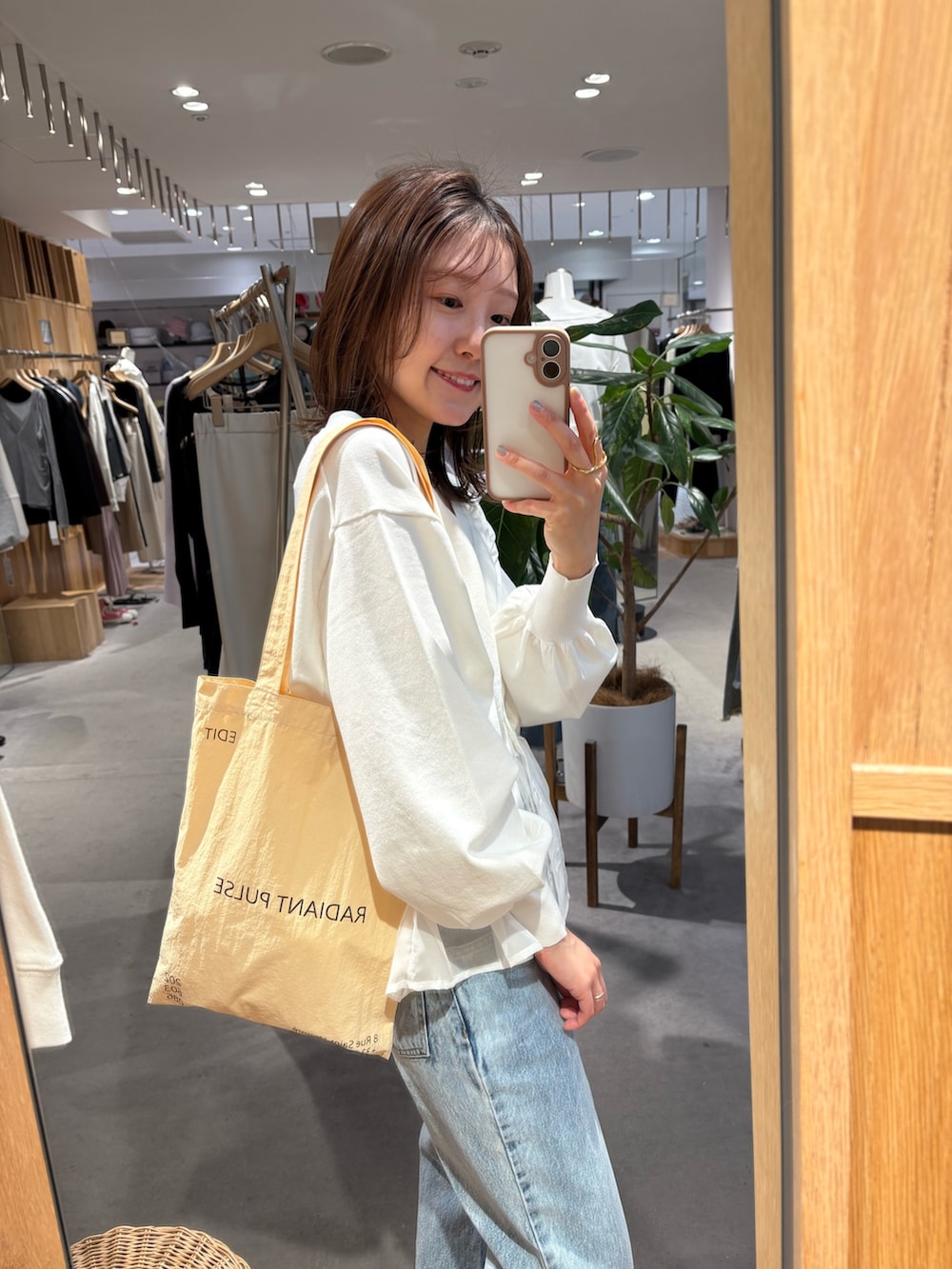 ホワイト系のカーディガン/ボレロ、ブルー系のデニムパンツ、イエロー系のトートバッグを着用したレディースの春コーディネートの3枚目の写真