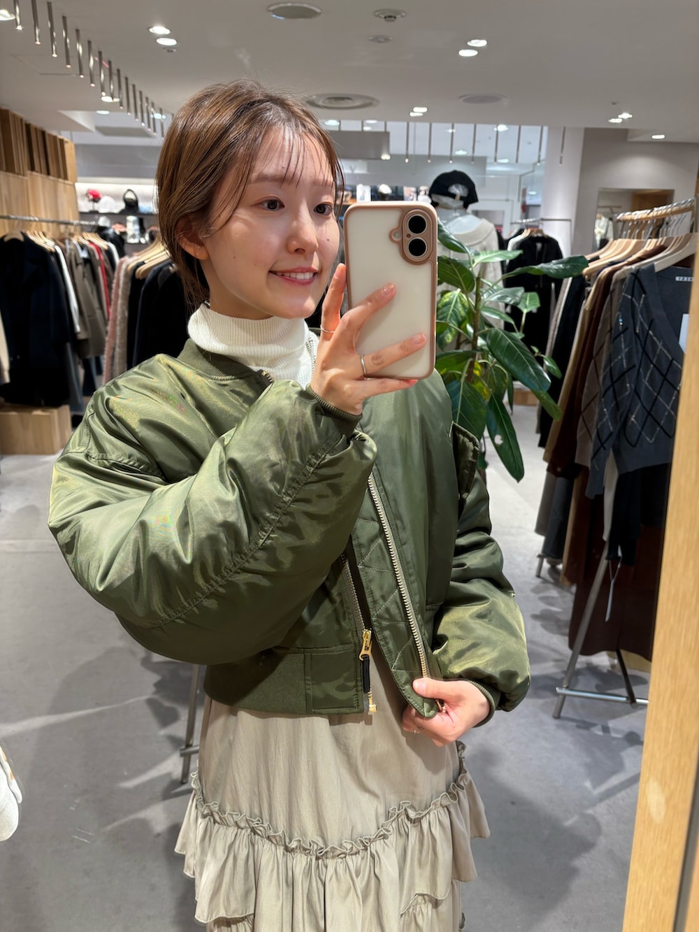 ベージュ系のワンピース、ホワイト系のニット/セーター、ブラック系のブーツを着用したレディースの冬コーディネートの3枚目の写真