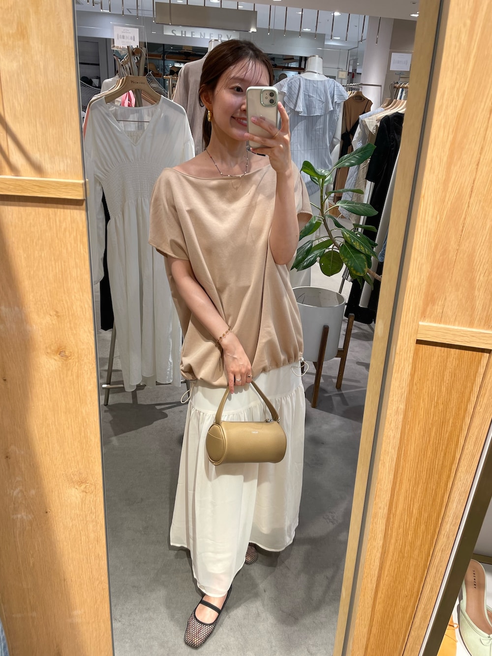 ベージュ系のスウェット、ホワイト系のスカート、ブラック系のパンプスを着用したレディースの夏コーディネートの2枚目の写真