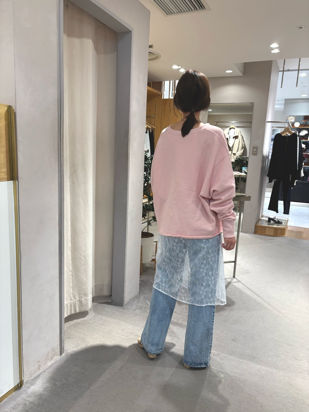 ピンク系のスウェット、ホワイト系のチュニック、ブルー系のデニムパンツを着用したレディースの春コーディネートの2枚目の写真