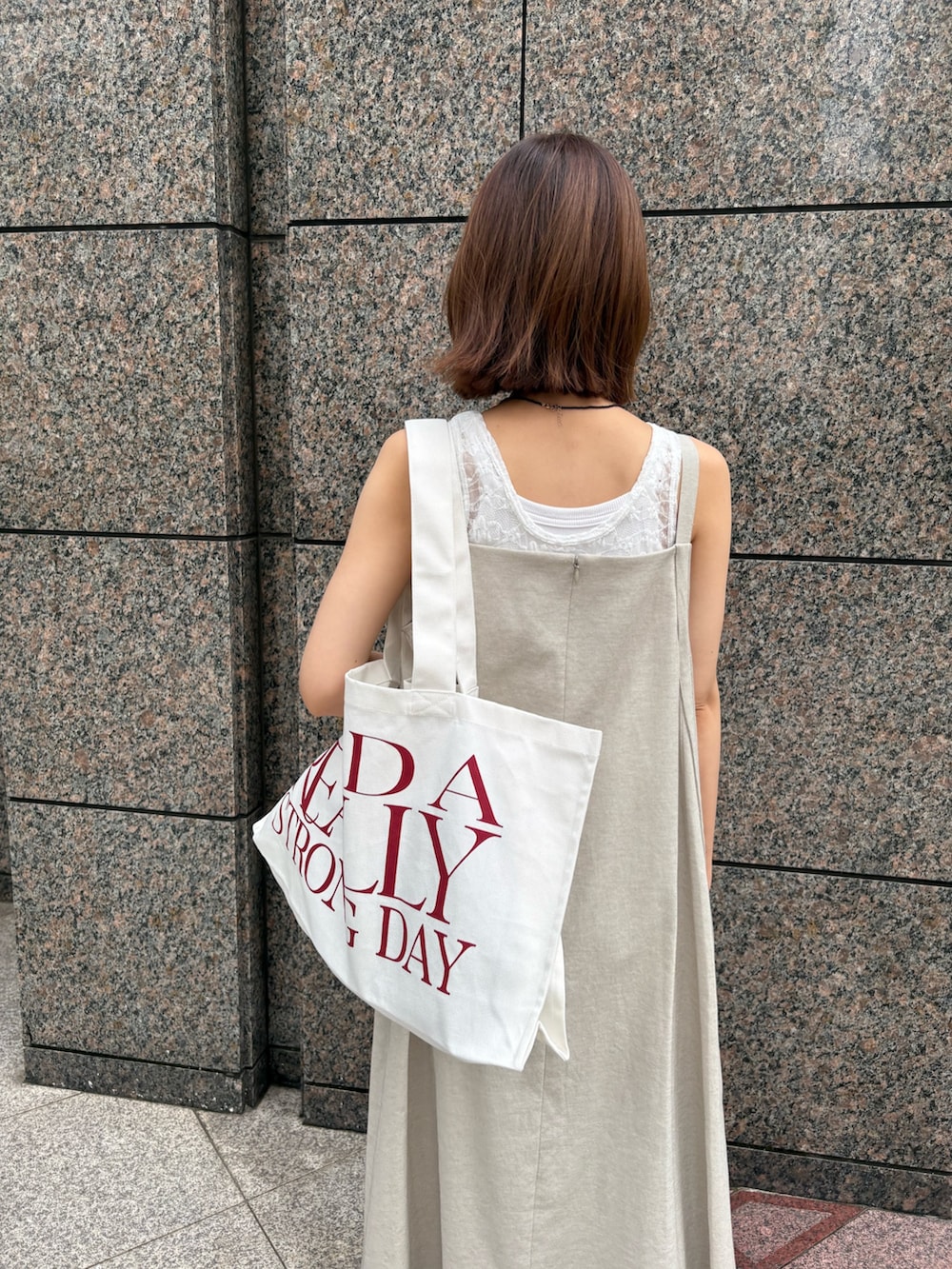 ベージュ系のワンピース、ホワイト系のTシャツ/カットソー、ホワイト系のトートバッグを着用したレディースの夏コーディネートの6枚目の写真