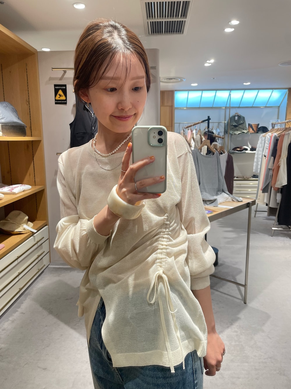 ホワイト系のニット/セーター、ベージュ系のキャミソール、ブルー系のデニムパンツを着用したレディースの秋コーディネートの2枚目の写真