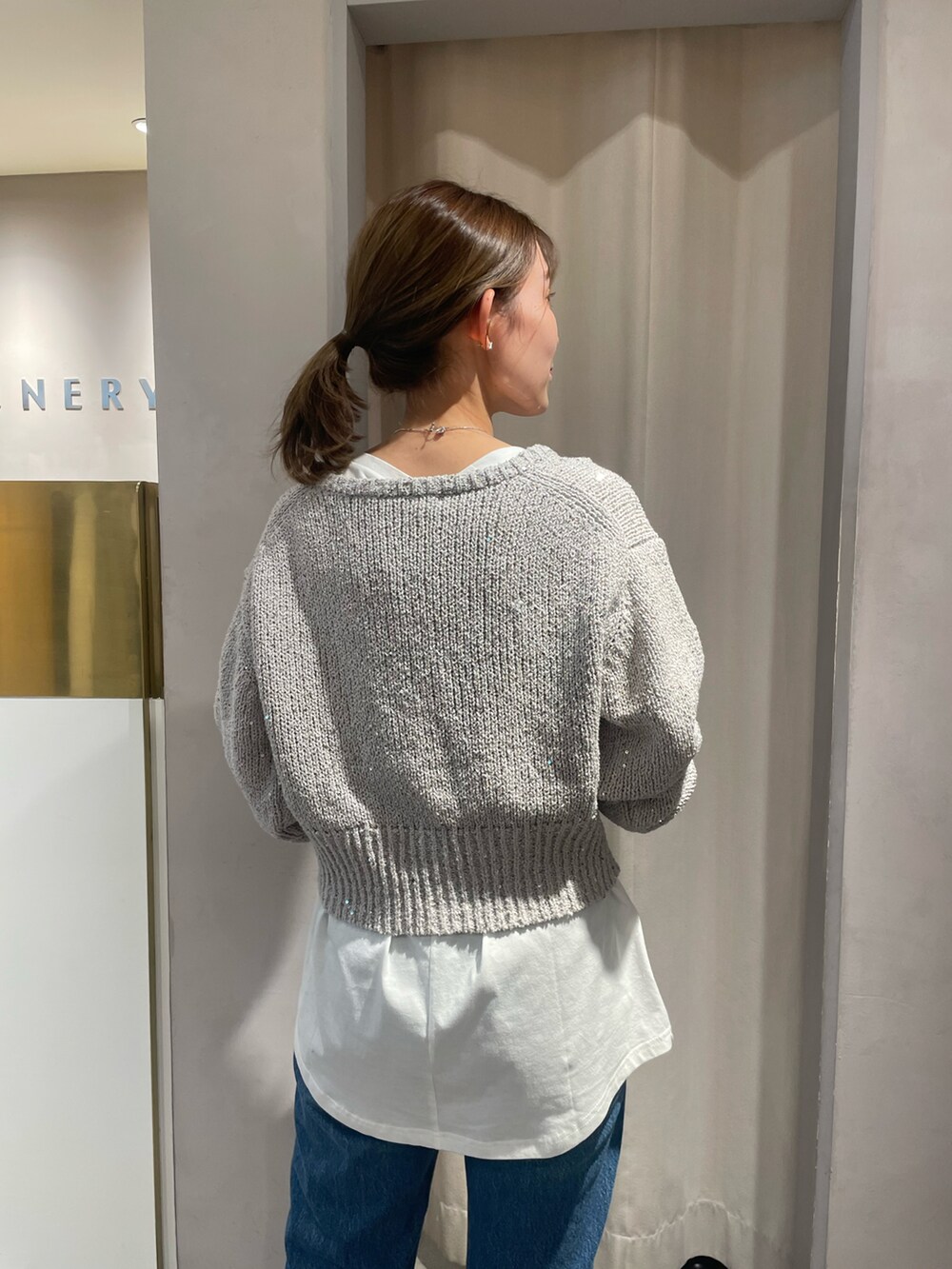 ブルー系のデニムパンツ、イエロー系のハンドバッグ、グレー系のカーディガン/ボレロを着用したレディースの冬コーディネートの4枚目の写真