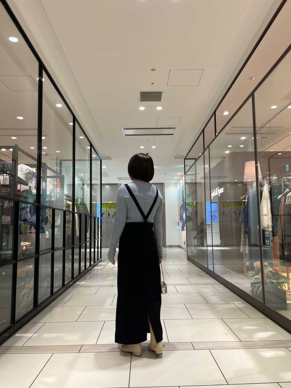 ホワイト系のブーツ、シルバー系のショルダーバッグ、ブラック系のワンピースを着用したレディースの冬コーディネートの3枚目の写真