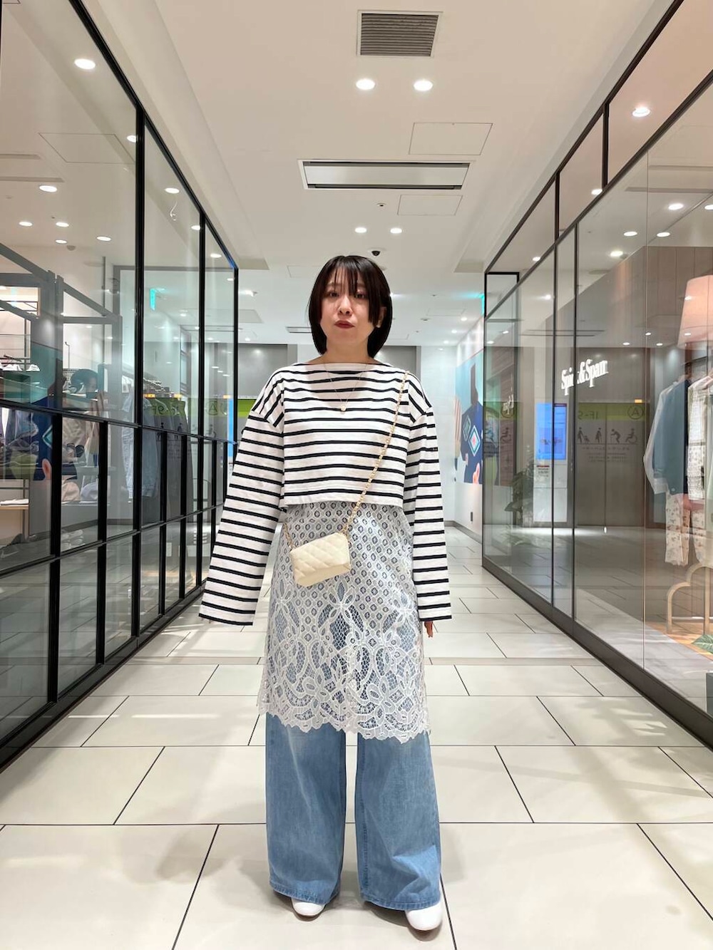 ホワイト系のショルダーバッグ、ホワイト系のワンピース、ブルー系のデニムパンツを着用したレディースの春コーディネートの3枚目の写真