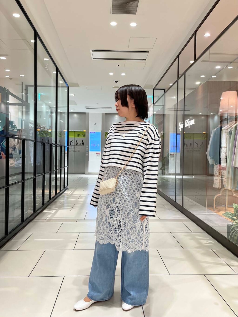 ホワイト系のショルダーバッグ、ホワイト系のワンピース、ブルー系のデニムパンツを着用したレディースの春コーディネートの2枚目の写真