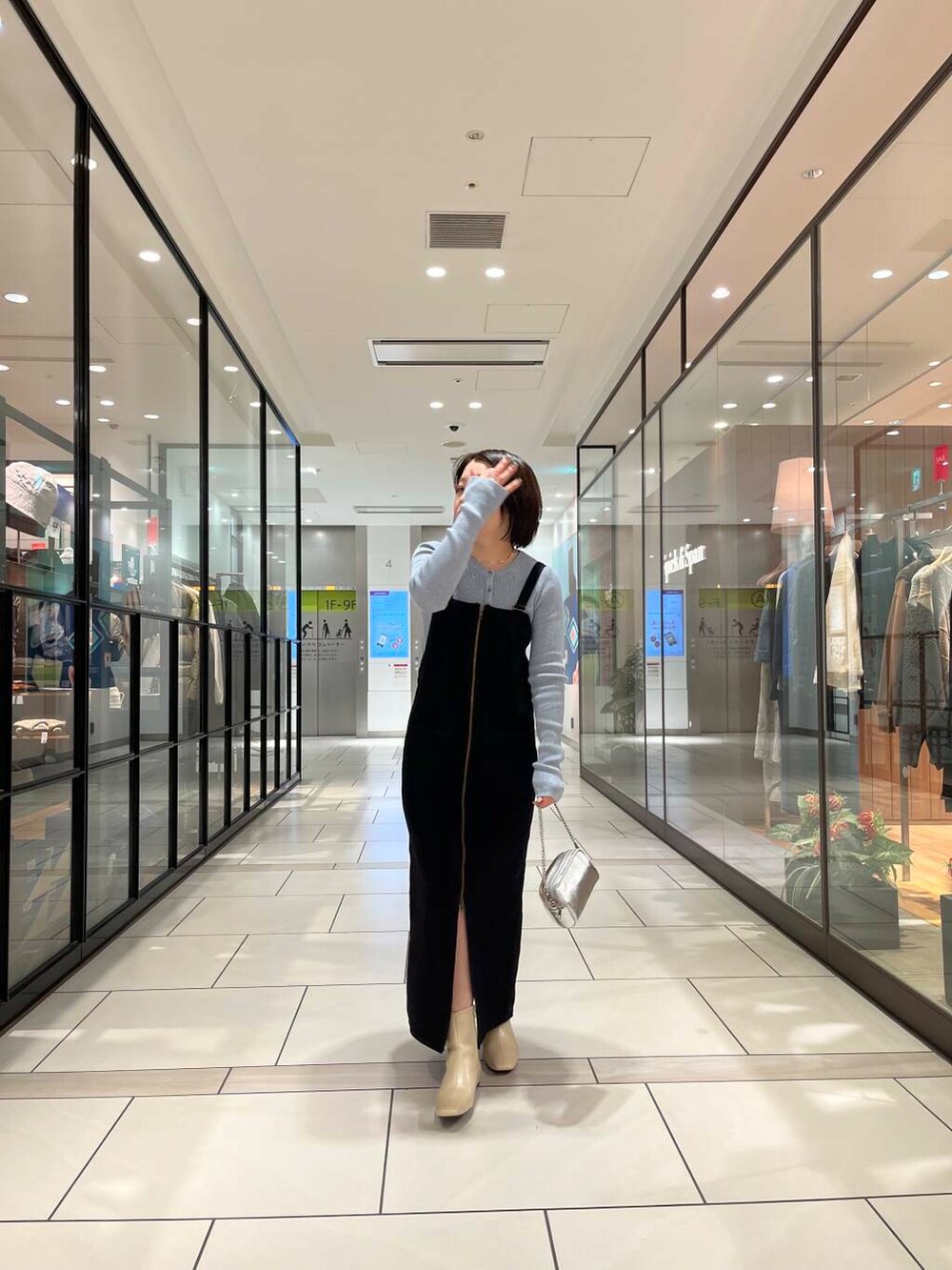 ホワイト系のブーツ、シルバー系のショルダーバッグ、ブラック系のワンピースを着用したレディースの冬コーディネートの2枚目の写真