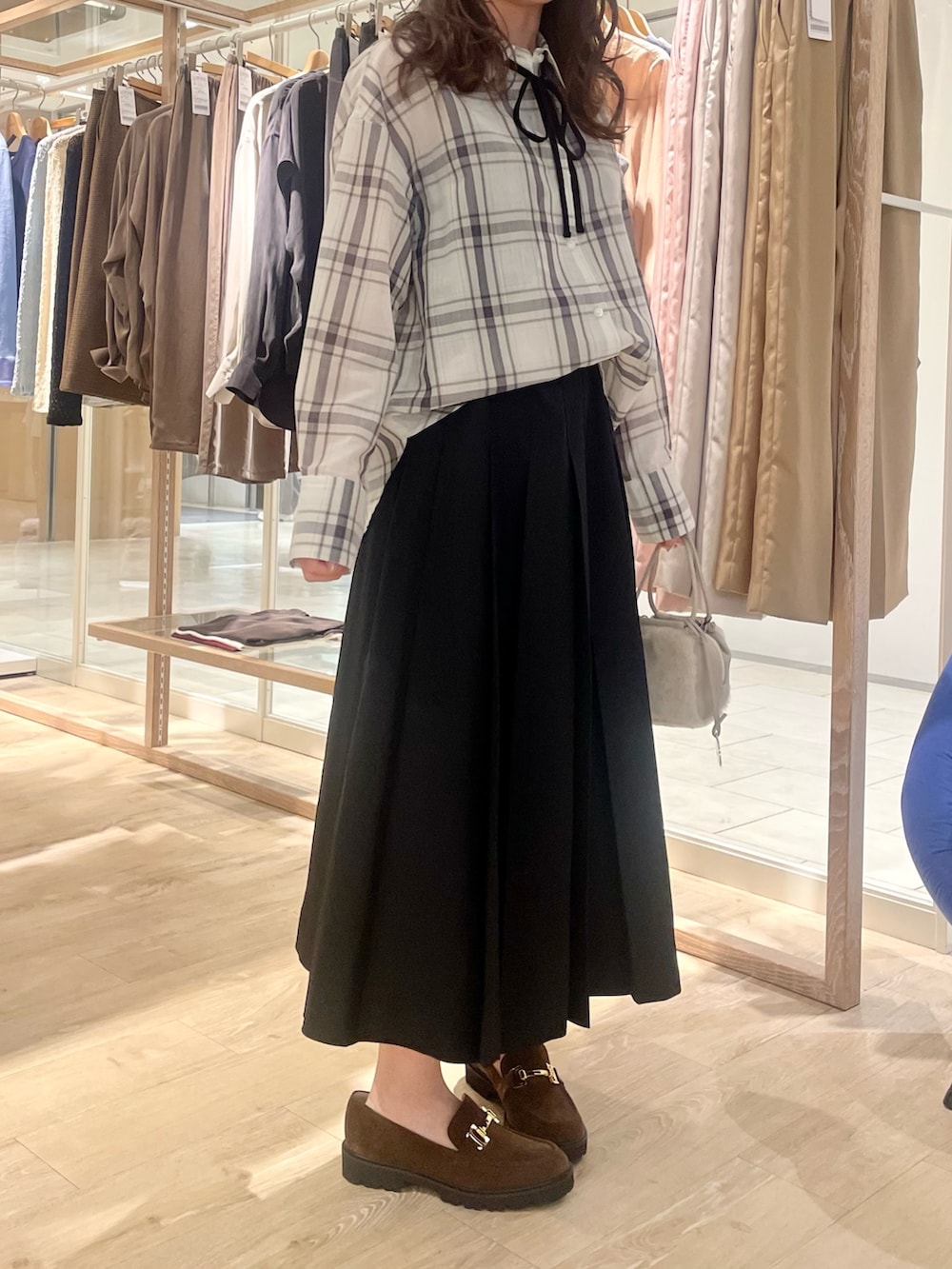 ブラック系のスカート、ブラウン系のローファー、ホワイト系のシャツ/ブラウスを着用したレディースの秋コーディネートの6枚目の写真