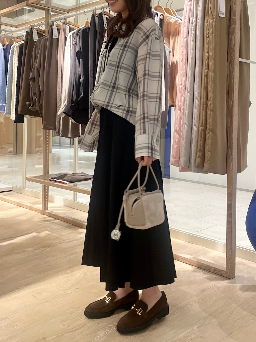 ブラック系のスカート、ブラウン系のローファー、ホワイト系のシャツ/ブラウスを着用したレディースの秋コーディネートの2枚目の写真