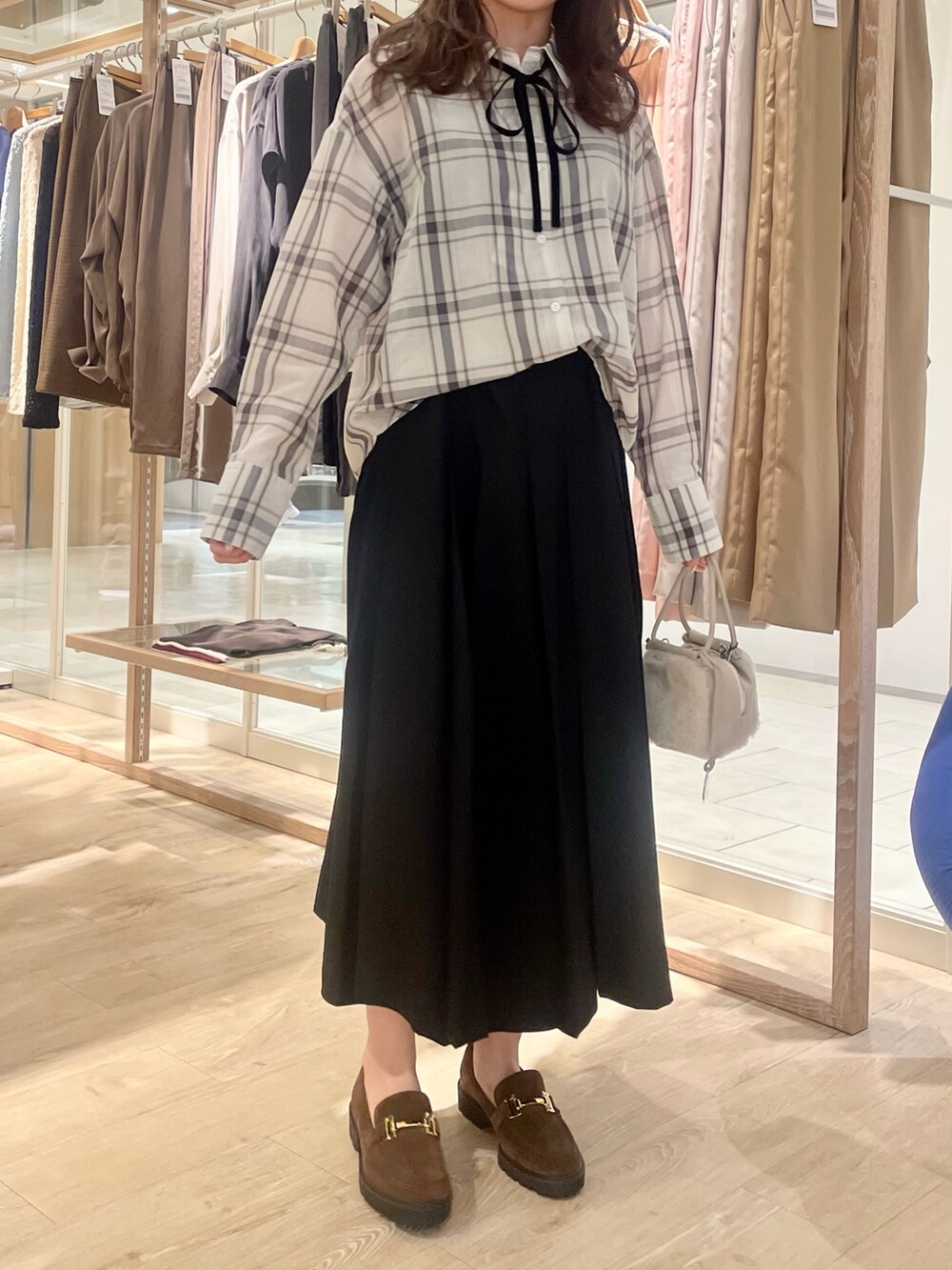 ブラック系のスカート、ブラウン系のローファー、ホワイト系のシャツ/ブラウスを着用したレディースの秋コーディネートの7枚目の写真