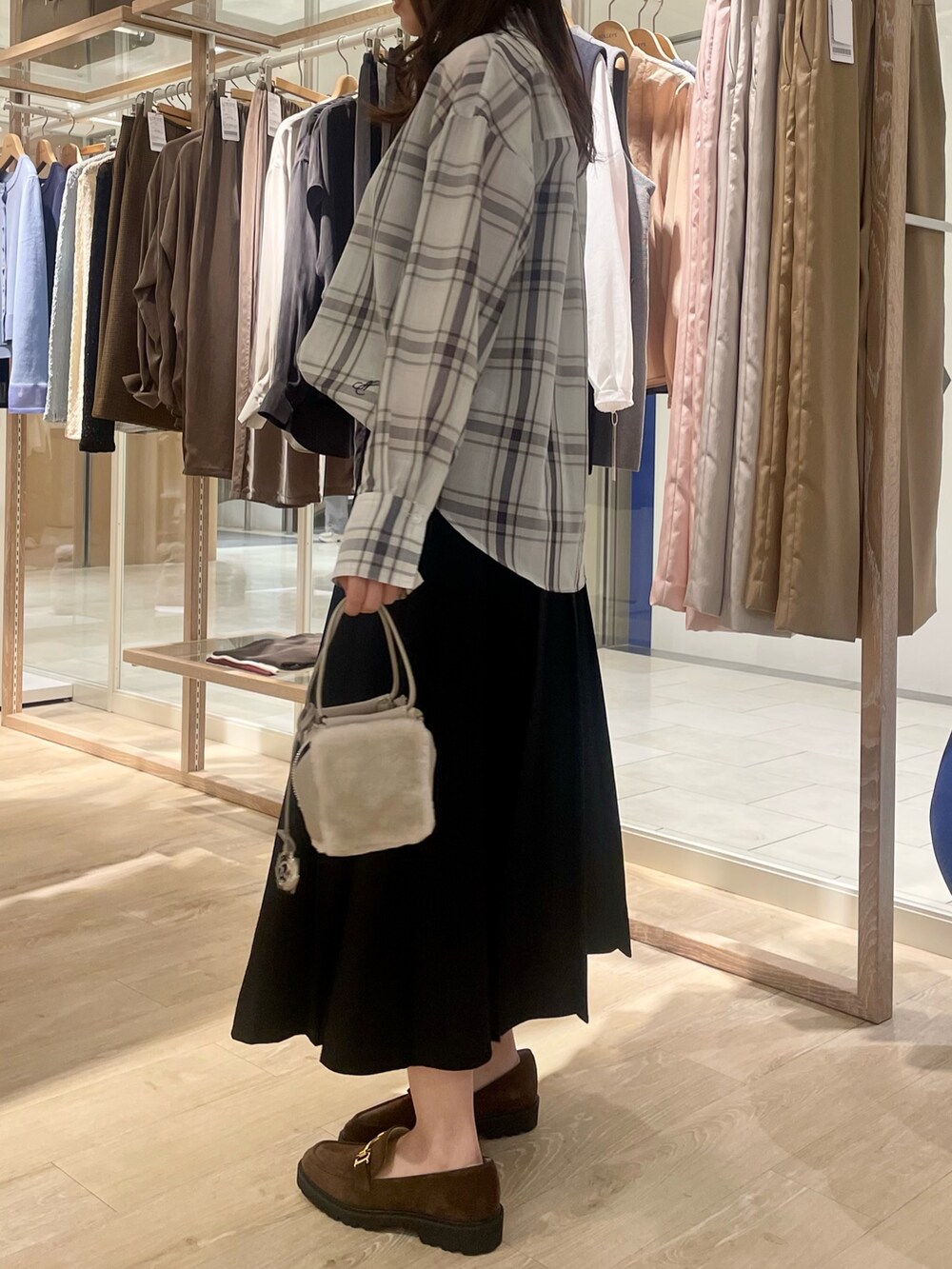 ブラック系のスカート、ブラウン系のローファー、ホワイト系のシャツ/ブラウスを着用したレディースの秋コーディネートの3枚目の写真