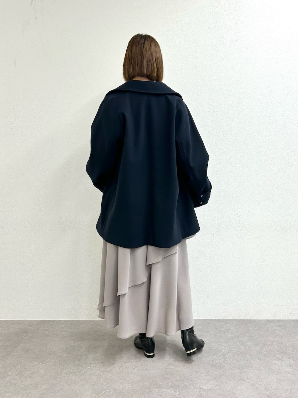 ブルー系のピーコート、ホワイト系のTシャツ/カットソー、ベージュ系のスカートを着用したレディースの秋コーディネートの4枚目の写真