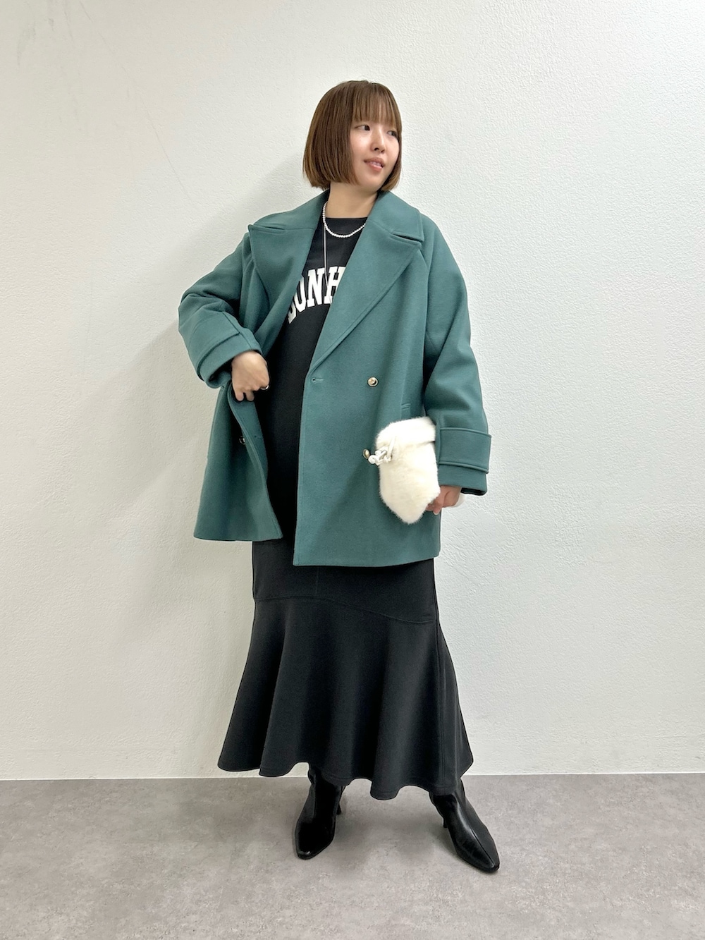 グリーン系のピーコート、グレー系のワンピースを着用したレディースの秋コーディネートの2枚目の写真