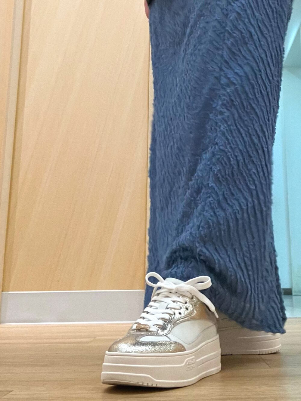 ゴールド系のスニーカーを着用したレディースの秋コーディネートの3枚目の写真