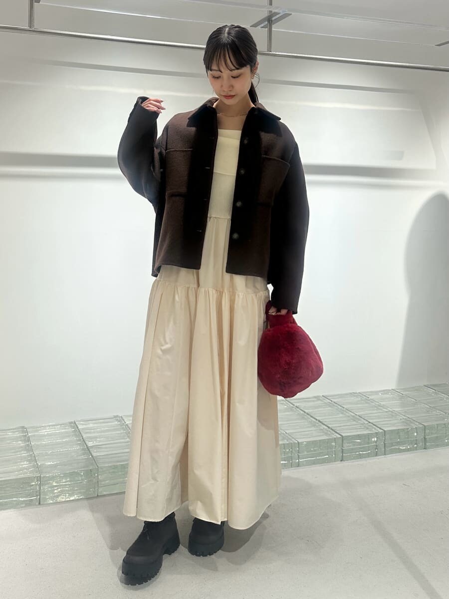 ブラウン系のチェスターコート、ホワイト系のワンピース、レッド系のハンドバッグを着用したレディースの秋コーディネートの2枚目の写真