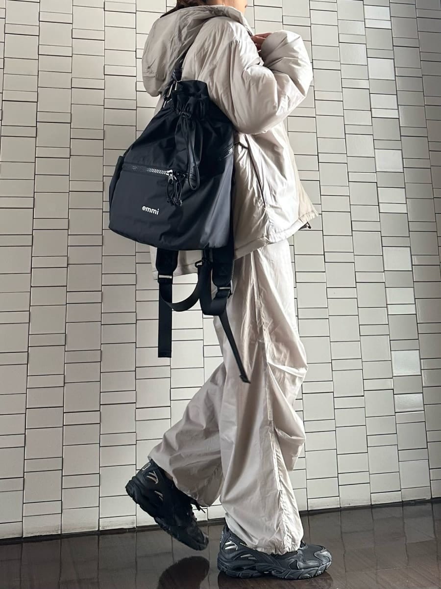 ブラック系のバックパック/リュック、ブラウン系のニット/セーター、ブラック系のスニーカーを着用したレディースの秋コーディネートの2枚目の写真