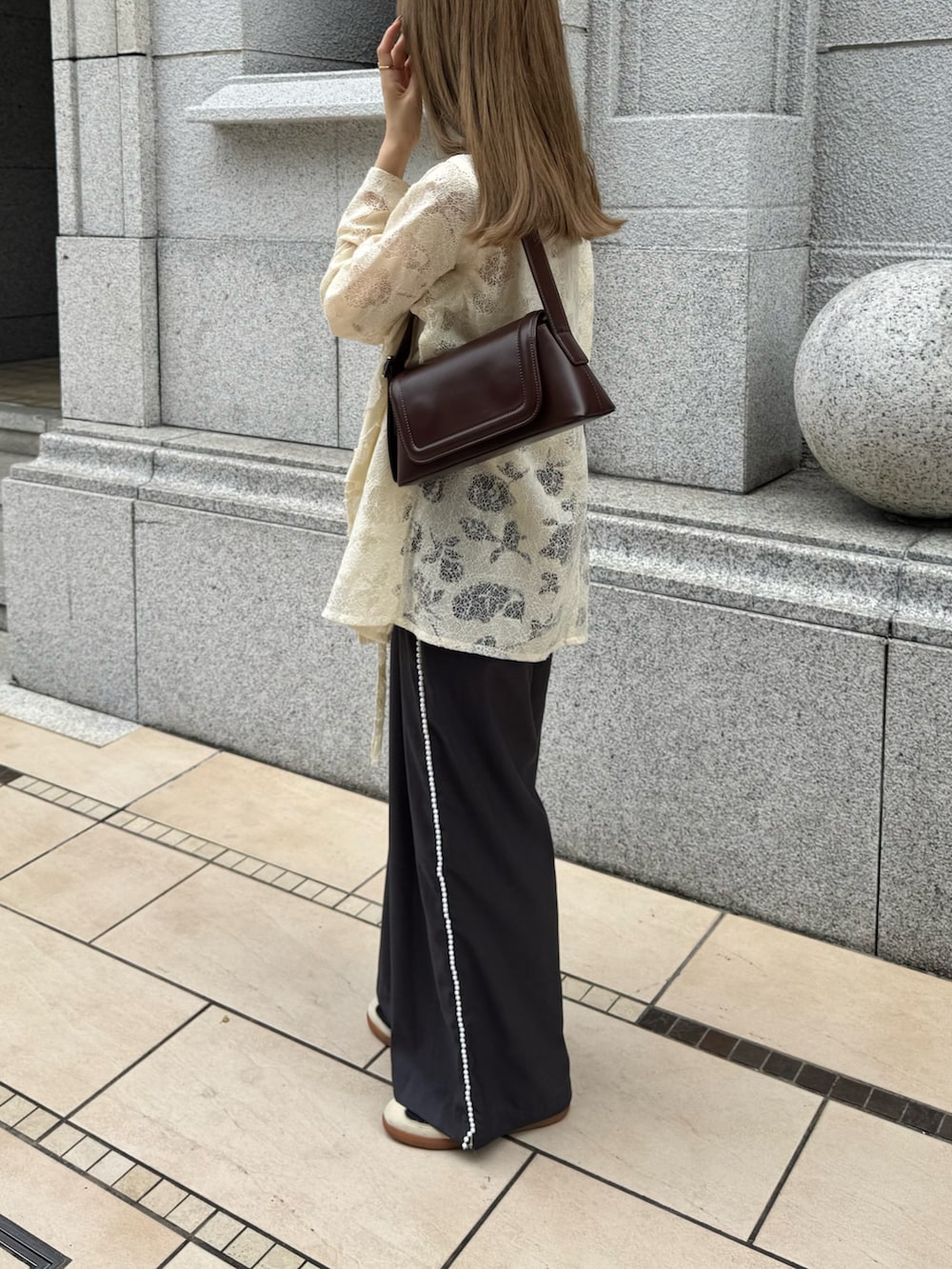 ホワイト系のテーラードジャケット、ブラウン系のショルダーバッグ、グレー系のスラックスを着用したレディースの秋コーディネートの2枚目の写真