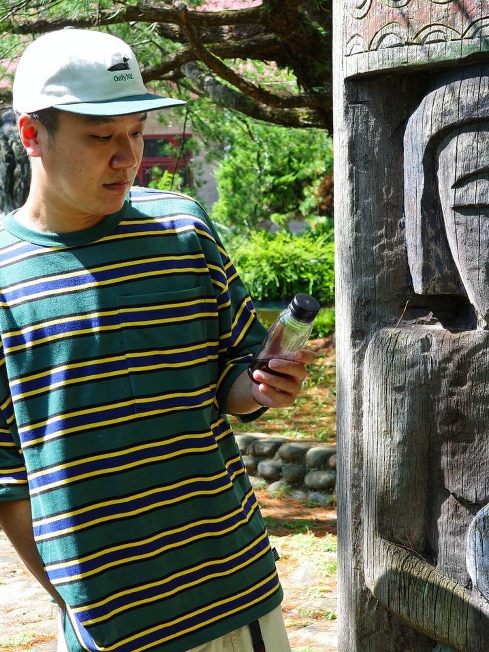 ベージュ系のカーゴパンツ、グリーン系のTシャツ/カットソー、ブラック系のシューズを着用したメンズの夏コーディネートの2枚目の写真