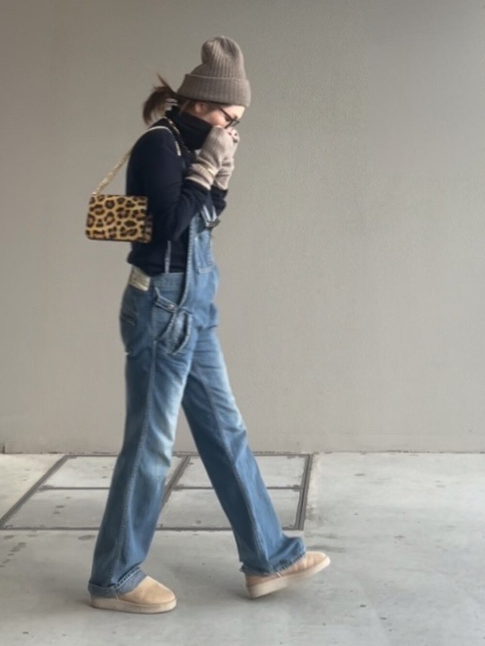 ブルー系のサロペット/オーバーオール、ブラウン系のバッグ、ベージュ系のニットキャップ/ビーニーを着用したレディースの秋コーディネートの2枚目の写真