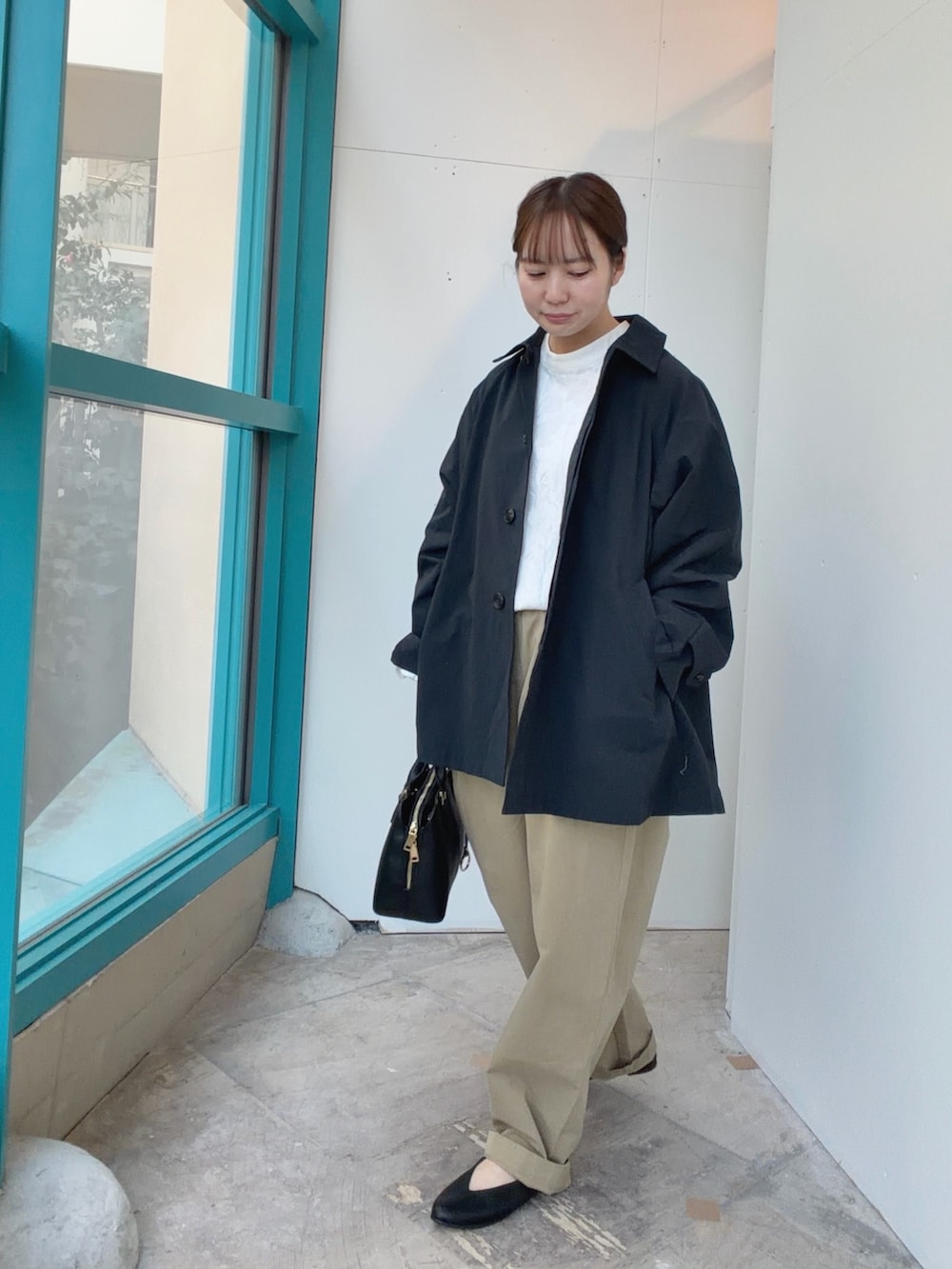 ブルー系のステンカラーコート、ブラック系のハンドバッグ、ベージュ系のその他パンツを着用したレディースの冬コーディネートの2枚目の写真