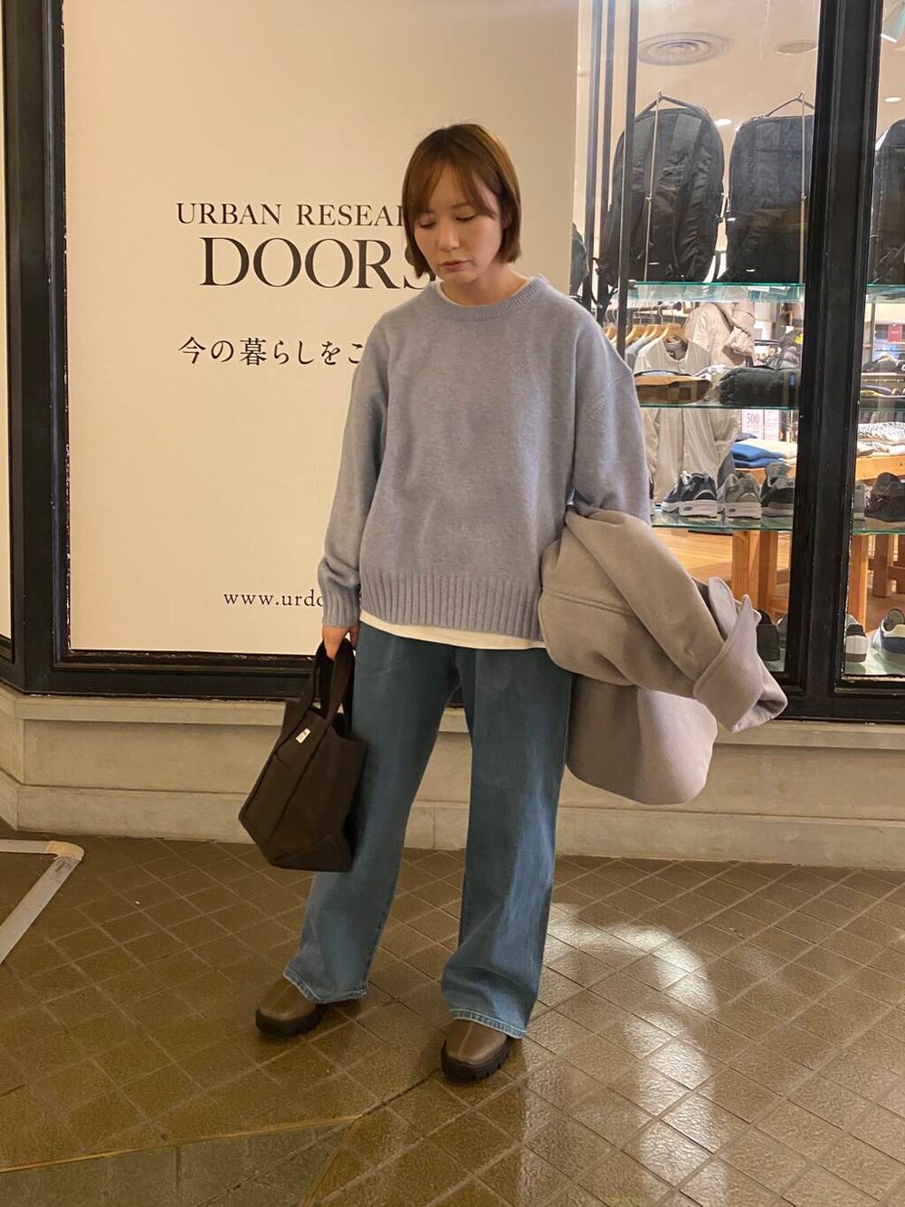 ブルー系のニット/セーター、ブラウン系のブーツ、グレー系のトートバッグを着用したレディースの冬コーディネートの2枚目の写真