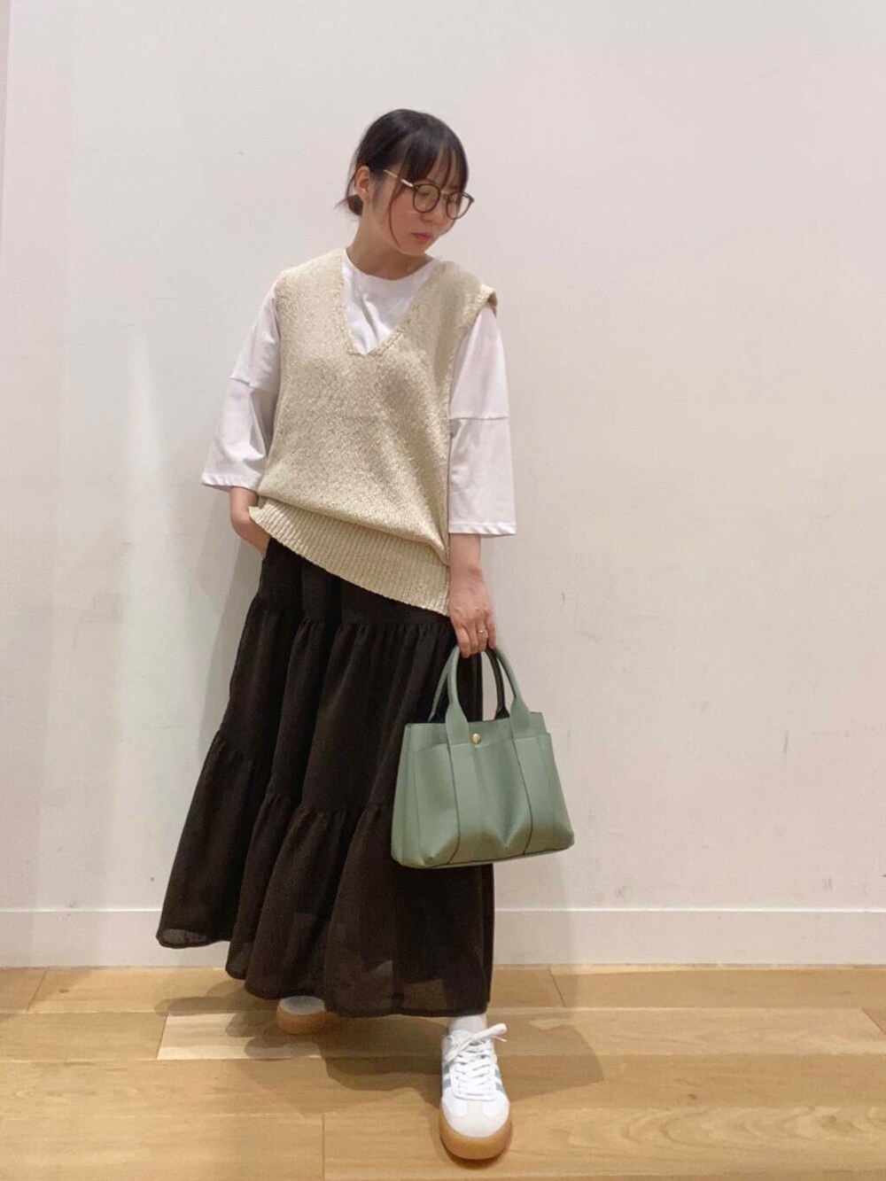グリーン系のトートバッグ、ホワイト系のTシャツ/カットソー、ブラウン系のスカートを着用したレディースの夏コーディネートの4枚目の写真