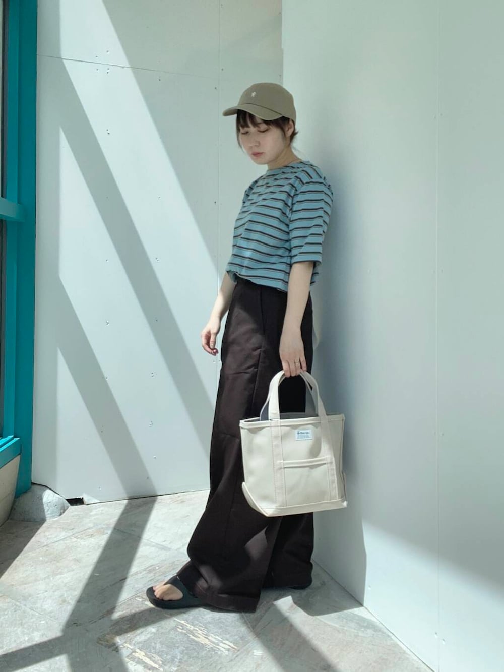 ベージュ系のトートバッグ、ブラウン系のその他パンツ、ブルー系のTシャツ/カットソーを着用したレディースの夏コーディネートの2枚目の写真