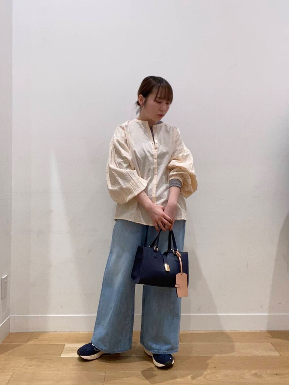 ブルー系のスニーカー、ブルー系のハンドバッグ、ブルー系のデニムパンツを着用したレディースの冬コーディネートの4枚目の写真