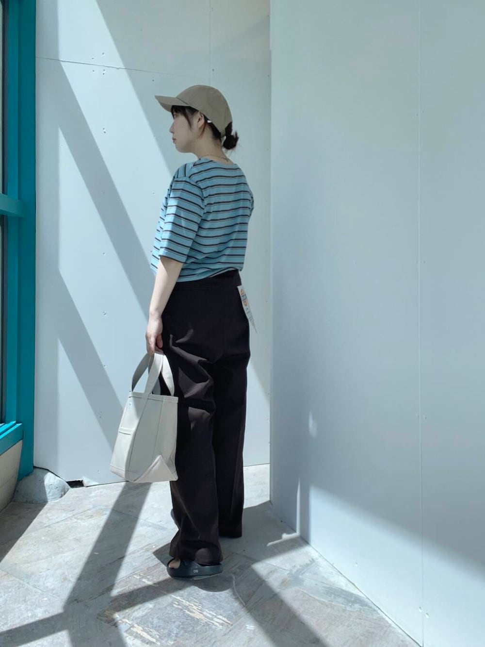 ベージュ系のトートバッグ、ブラウン系のその他パンツ、ブルー系のTシャツ/カットソーを着用したレディースの夏コーディネートの3枚目の写真