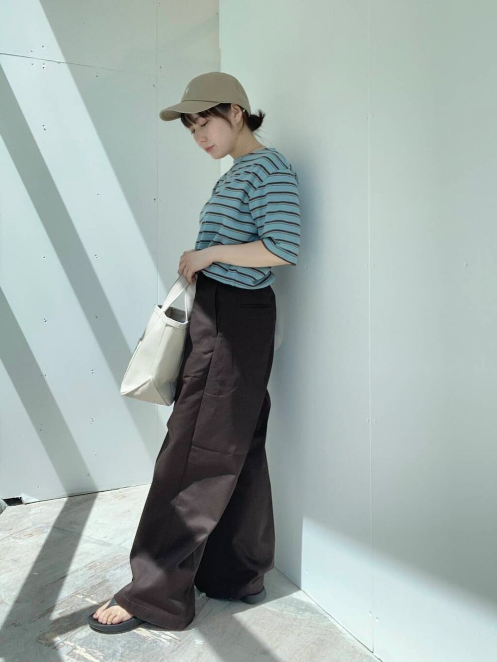 ベージュ系のトートバッグ、ブラウン系のその他パンツ、ブルー系のTシャツ/カットソーを着用したレディースの夏コーディネートの5枚目の写真