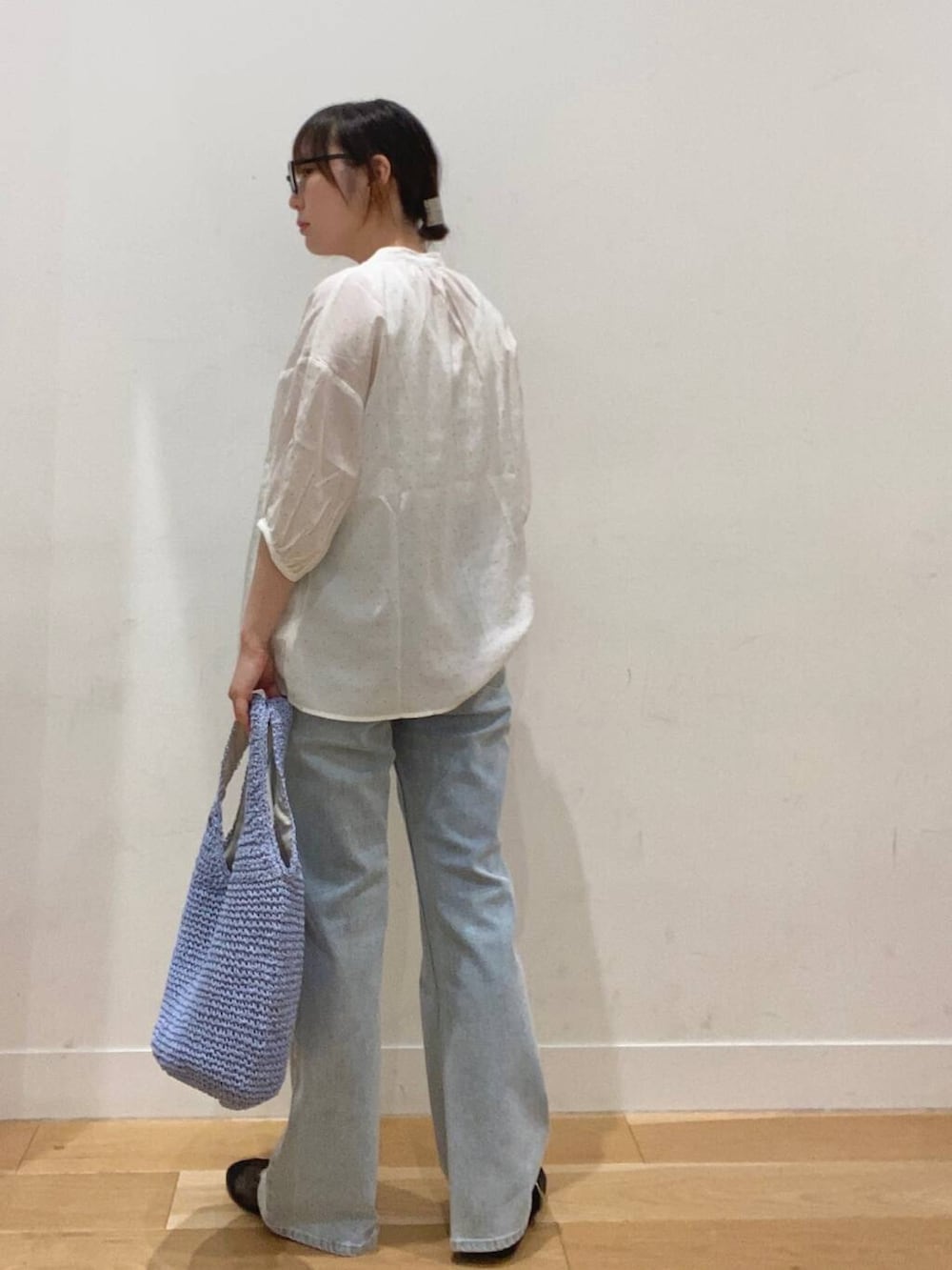 ブルー系のトートバッグ、ブルー系のデニムパンツ、ホワイト系のタンクトップを着用したレディースの夏コーディネートの2枚目の写真