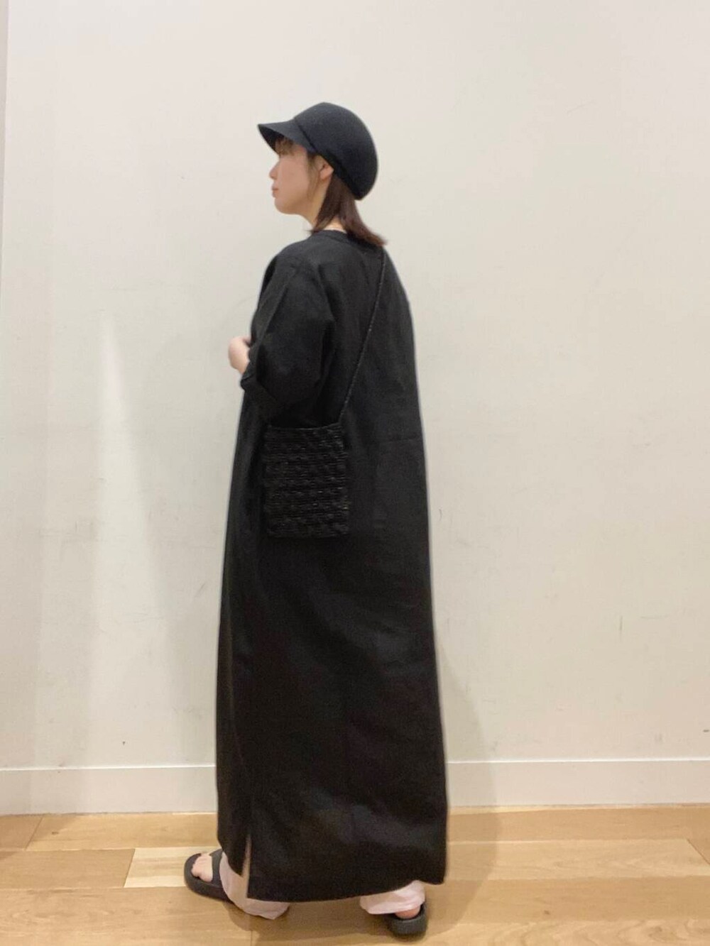 ブラック系のワンピース、ブラック系のサンダル、ブラック系のショルダーバッグを着用したレディースの春コーディネートの2枚目の写真