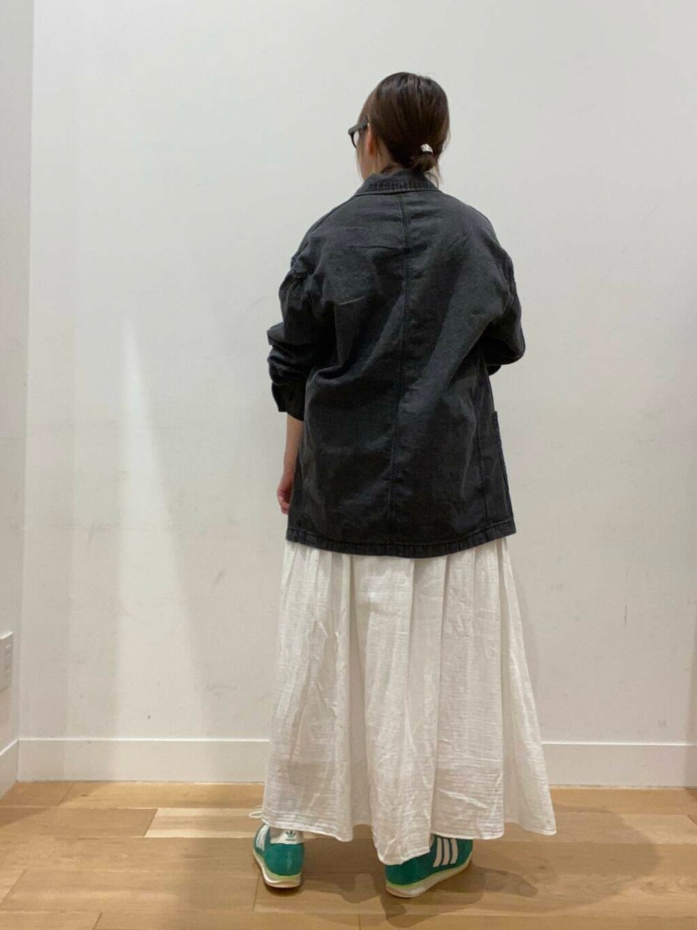 ホワイト系のスカート、ブラック系のカバーオール、ホワイト系のTシャツ/カットソーを着用したレディースの冬コーディネートの3枚目の写真