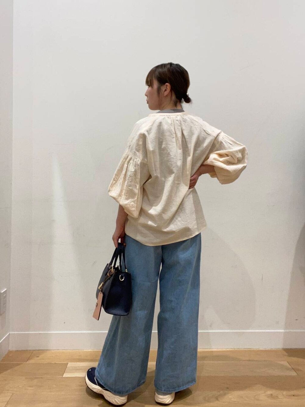 ブルー系のスニーカー、ブルー系のハンドバッグ、ブルー系のデニムパンツを着用したレディースの冬コーディネートの3枚目の写真