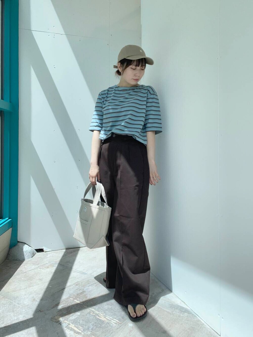 ベージュ系のトートバッグ、ブラウン系のその他パンツ、ブルー系のTシャツ/カットソーを着用したレディースの夏コーディネートの4枚目の写真