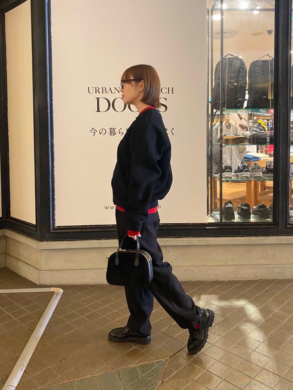 レッド系のニット/セーター、ブラック系のショルダーバッグ、ブラック系のカーディガン/ボレロを着用したレディースの秋コーディネートの2枚目の写真