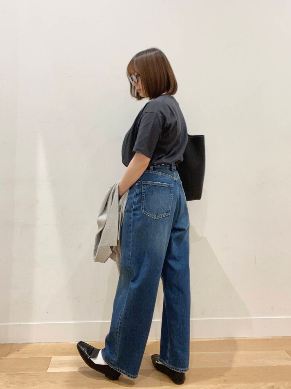 ブラック系のローファー、ブルー系のデニムパンツ、ブラック系のトートバッグを着用したレディースの春コーディネートの4枚目の写真