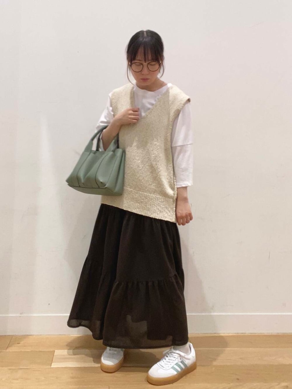 グリーン系のトートバッグ、ホワイト系のTシャツ/カットソー、ブラウン系のスカートを着用したレディースの夏コーディネートの2枚目の写真