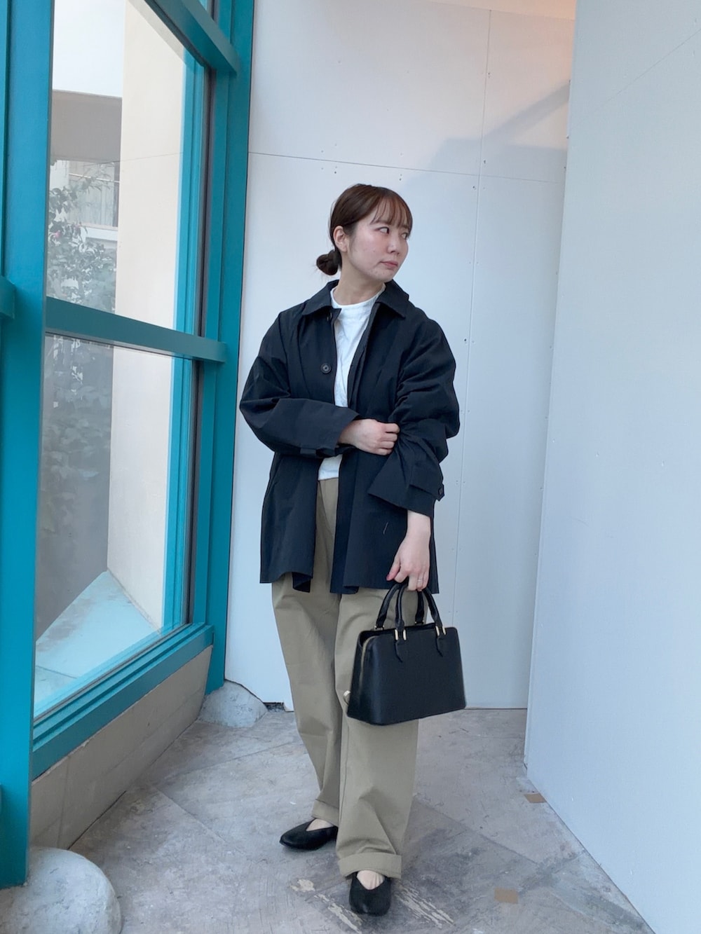 ブルー系のステンカラーコート、ブラック系のハンドバッグ、ベージュ系のその他パンツを着用したレディースの冬コーディネートの3枚目の写真