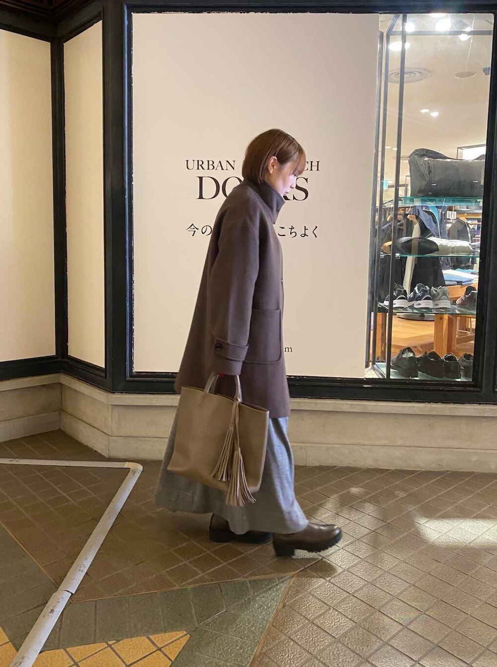 グレー系のトートバッグ、ブラウン系のブーツ、ブラウン系のその他アウターを着用したレディースの秋コーディネートの2枚目の写真