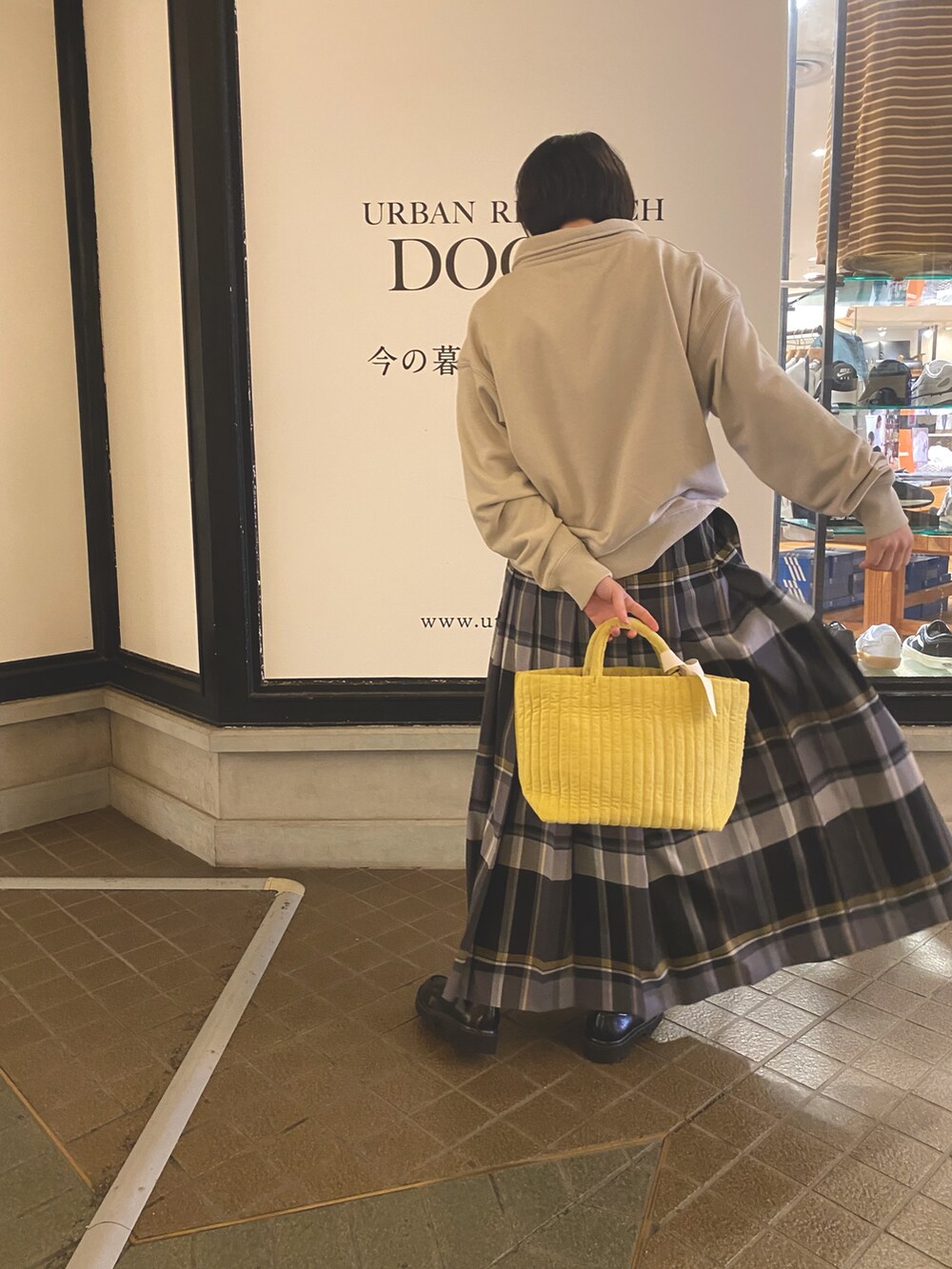 イエロー系のトートバッグ、ブラック系のスカート、ベージュ系のスウェットを着用したレディースの秋コーディネートの4枚目の写真