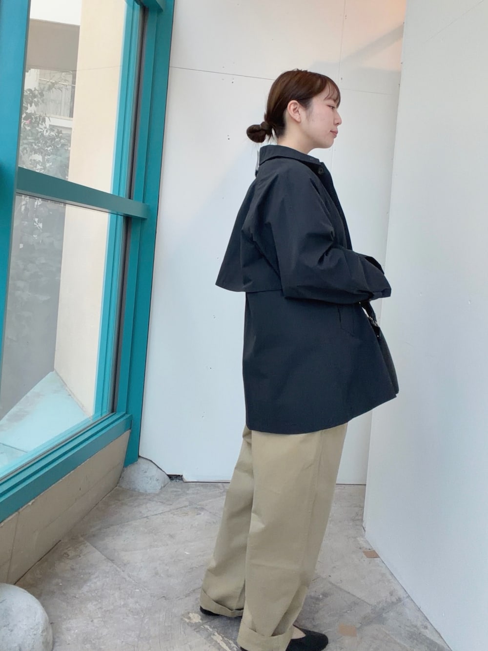 ブルー系のステンカラーコート、ブラック系のハンドバッグ、ベージュ系のその他パンツを着用したレディースの冬コーディネートの4枚目の写真